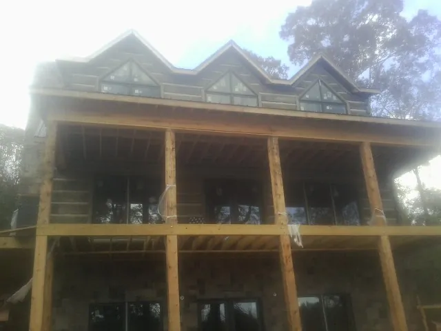 Dormers and porch framing on a large log home under construction — Roof Coating work by our crew in Keyes